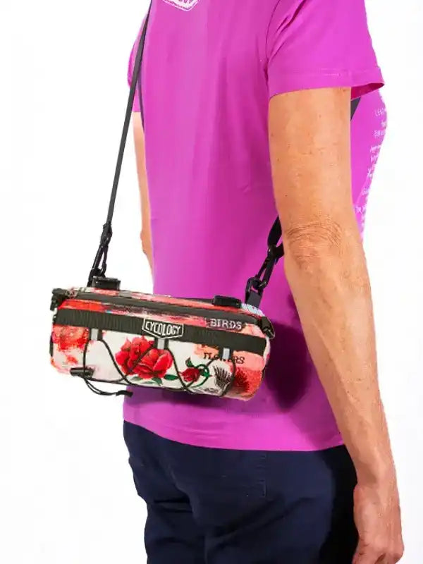Cycling bag with floral rose print, worn crossbody by cyclist in pink jersey