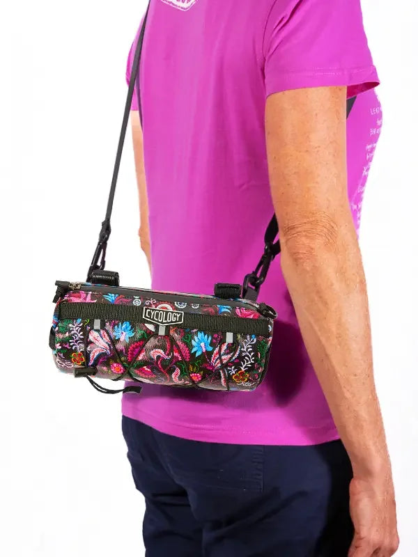 Cycology floral cycling bag with adjustable strap, worn over shoulder by cyclist in pink jersey