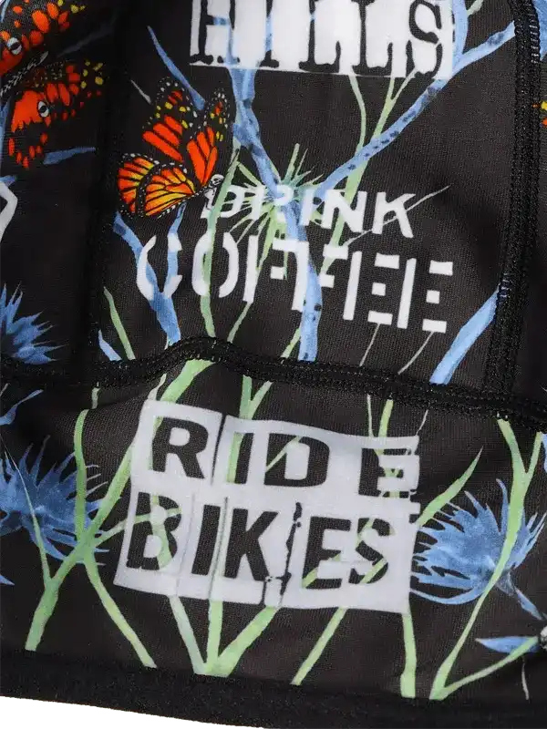 Black cycling jersey with butterfly print, 'Drink Coffee Ride Bikes' text, and rear pockets