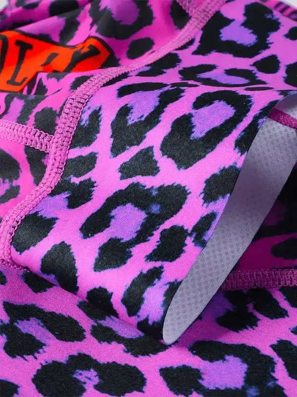 Vibrant pink leopard print cycling shorts with black spots and orange logo detail