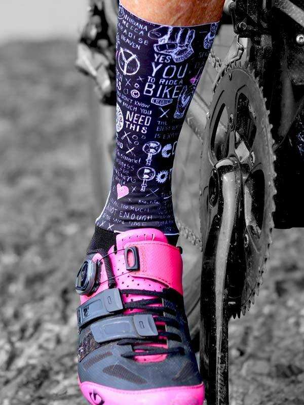 Cycling socks with bike-themed graphics and pink cycling shoe on bike pedal