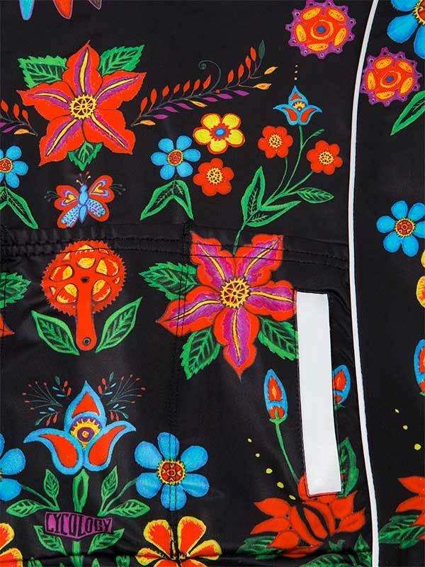 Vibrant floral cycling jersey with bold red, blue, and green flowers on black fabric, featuring reflective strip and brand logo.