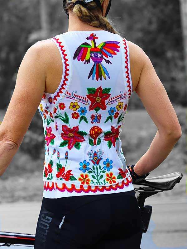 Woman wearing colorful floral and bird print cycling jersey, back view on bike