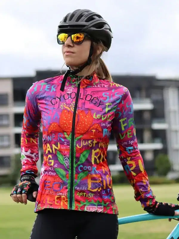 Woman in vibrant graffiti-style cycling jersey, helmet, and sunglasses, ready for a ride.