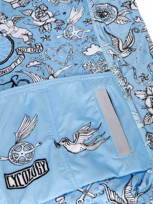Light blue cycling shorts with tattoo-style bird, gear, and rose print, featuring reflective strip and Cycology logo