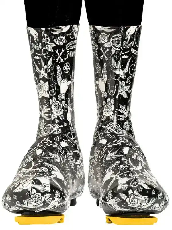 Black and white patterned cycling shoe covers with floral and bike motifs, worn over cleats