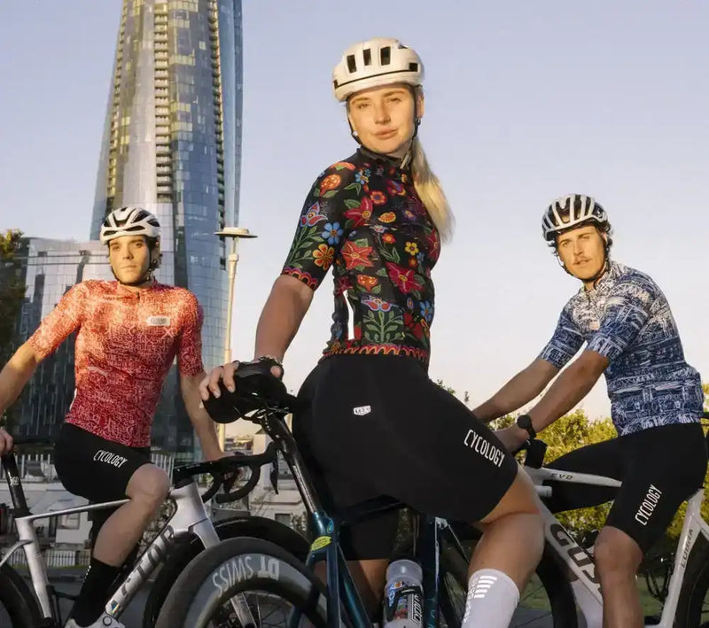Cyclists in colorful floral and patterned cycling jerseys and shorts, riding bikes in urban setting