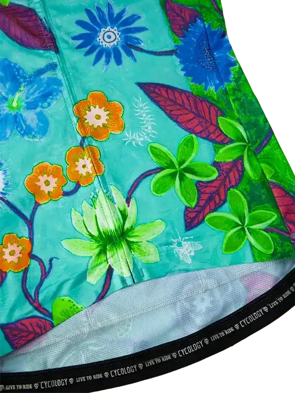 Vibrant floral cycling jersey with green, blue, and orange blooms on teal fabric, featuring branded hem detail.
