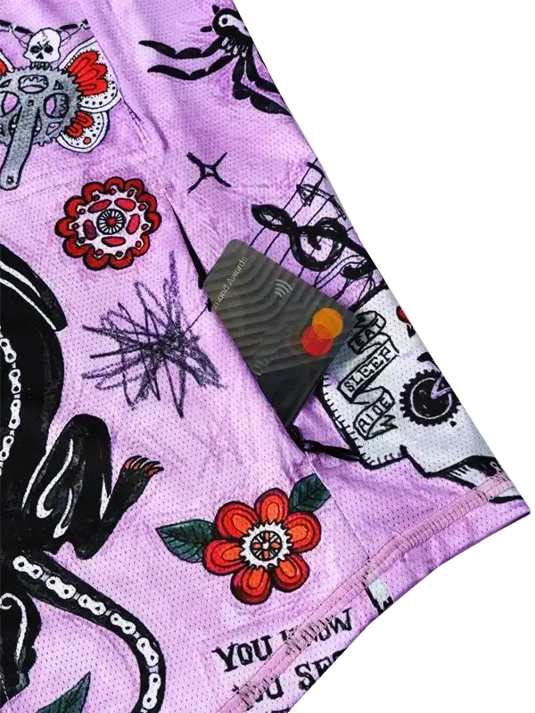 Purple cycling shorts with bold tattoo-style designs, including skulls, flowers, and music notes.