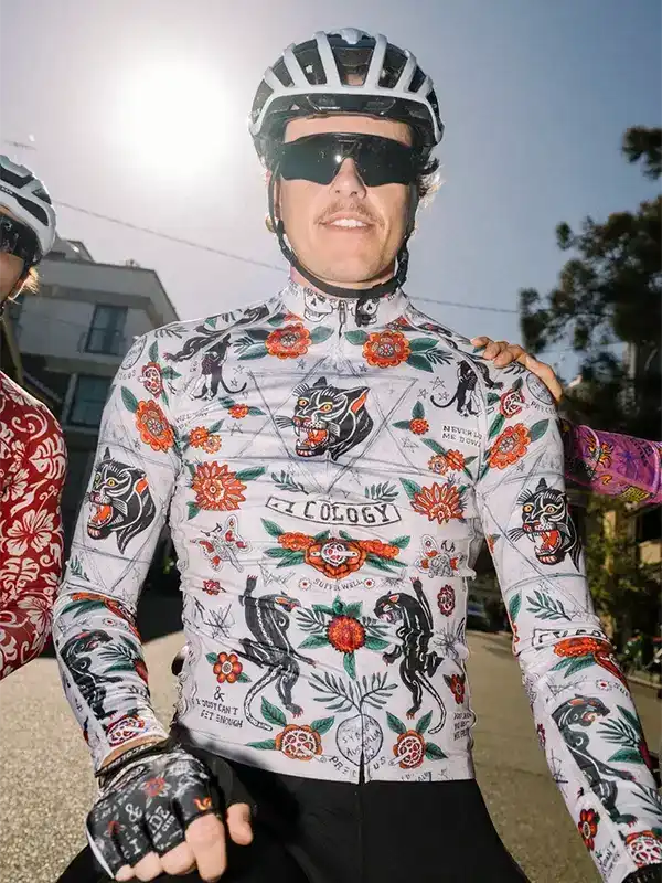 Men's cycling jersey with bold floral and panther print, worn with helmet and sunglasses for road biking.