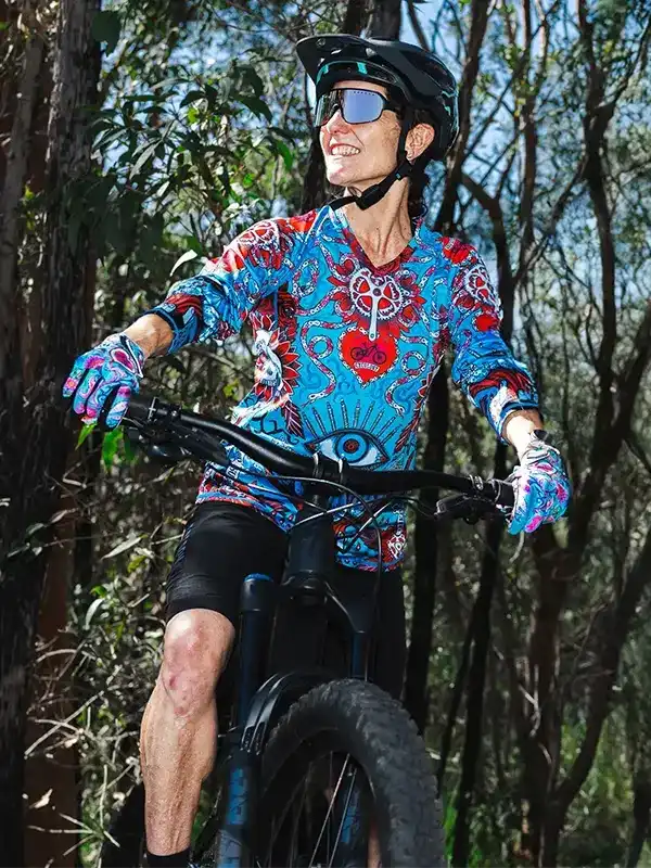 Woman cycling in vibrant patterned jersey and gloves on forest trail