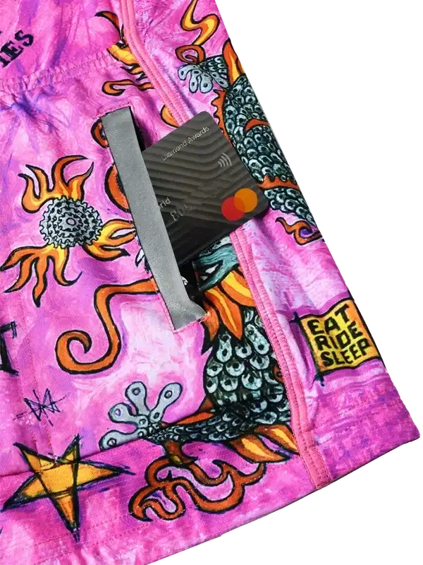 Vibrant pink cycling shorts with bold dragon and flame designs, featuring 'EAT RIDE SLEEP' text.