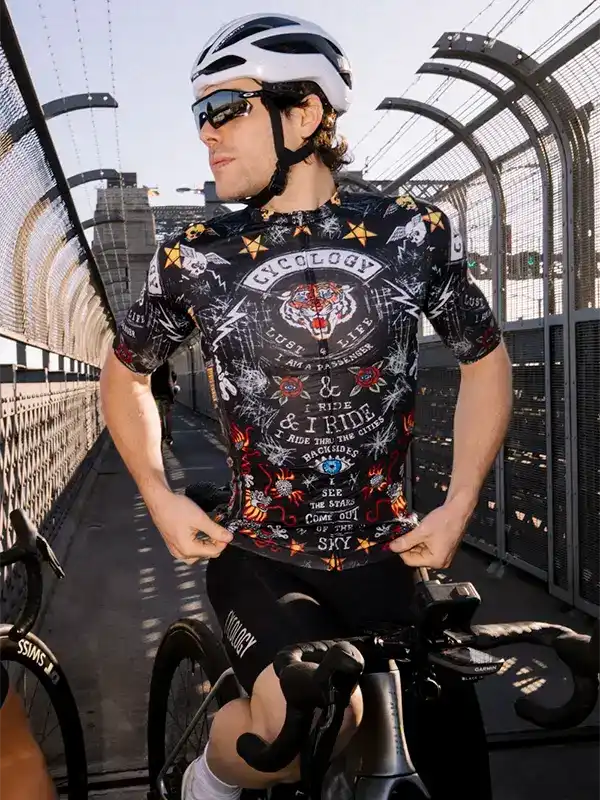 Man wearing graphic cycling jersey and helmet on bridge, ready to ride