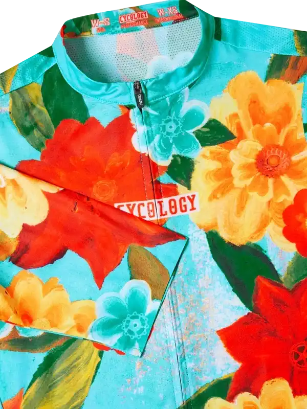 Vibrant floral cycling jersey with bold red, orange, and teal flowers on a turquoise background.