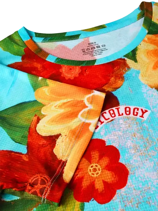 Vibrant floral cycling jersey with bold red, orange, and teal print, featuring 'Cycology' logo on sleeve