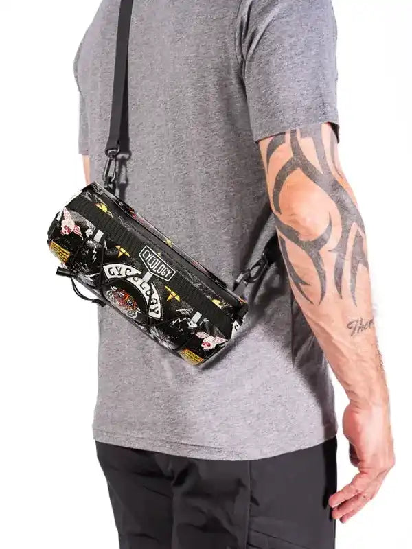 Cycology branded crossbody bag with bold graphic print, worn by man with tattooed arm