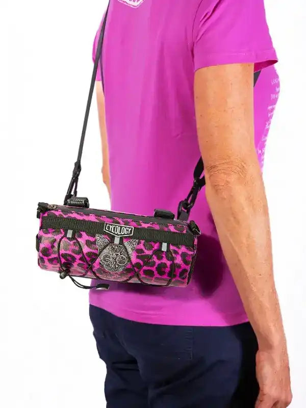 Pink leopard print cycling frame bag with black straps, worn by cyclist in magenta jersey