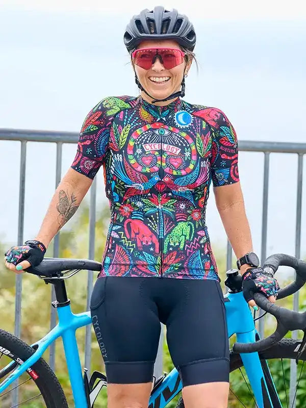 Woman in vibrant cycling jersey and helmet, standing with blue bike, showcasing unique design