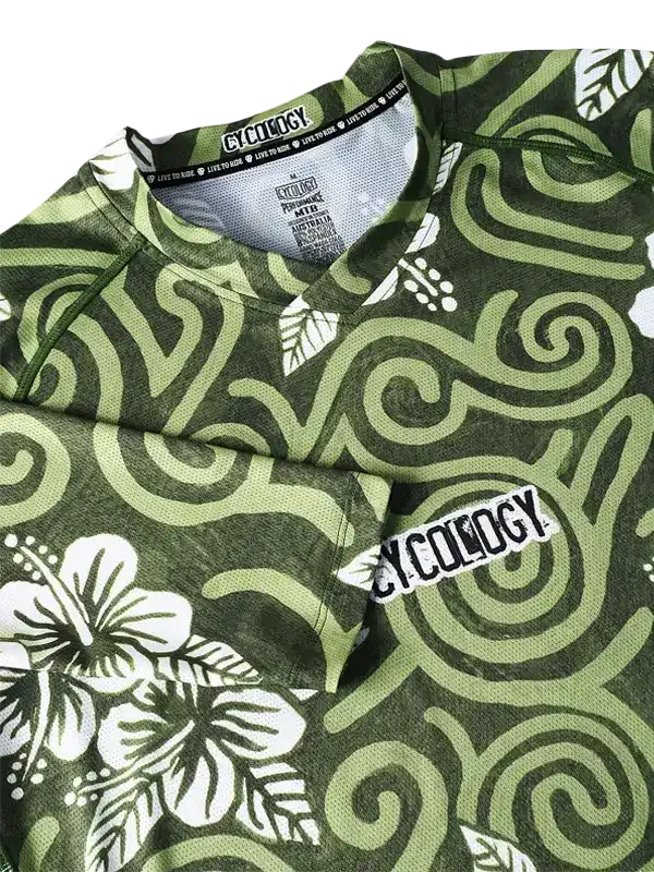 Green cycling jersey with white hibiscus and swirl pattern, featuring Cycology logo on chest