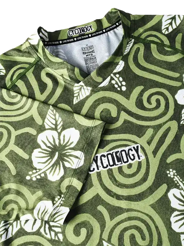 Green cycling jersey with white hibiscus flowers and swirl patterns, featuring 'Cycology' logo on chest