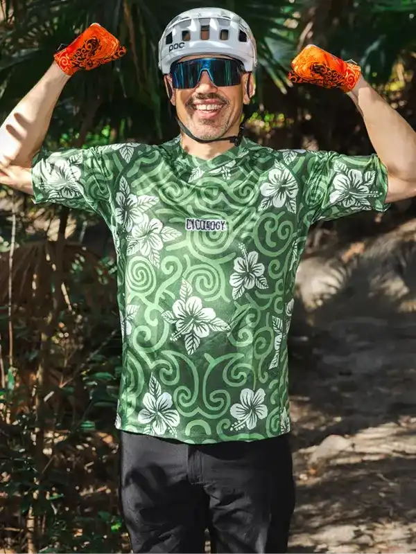 Man wearing green floral cycling jersey, helmet, and orange gloves outdoors