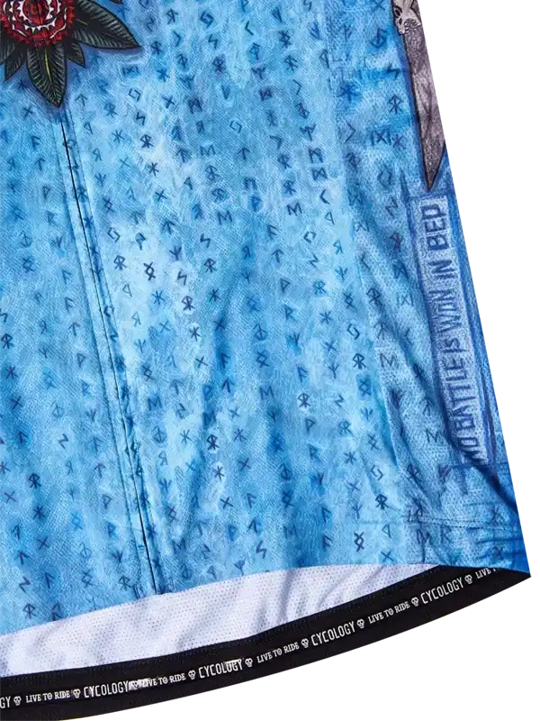 Blue cycling jersey with rune pattern, floral graphic, and 'No Battle Is Won In Bed' text, featuring Cycology branding on hem
