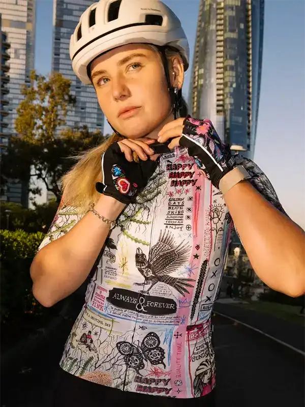 Woman in colorful graphic cycling jersey and helmet, urban city backdrop, stylish bike wear