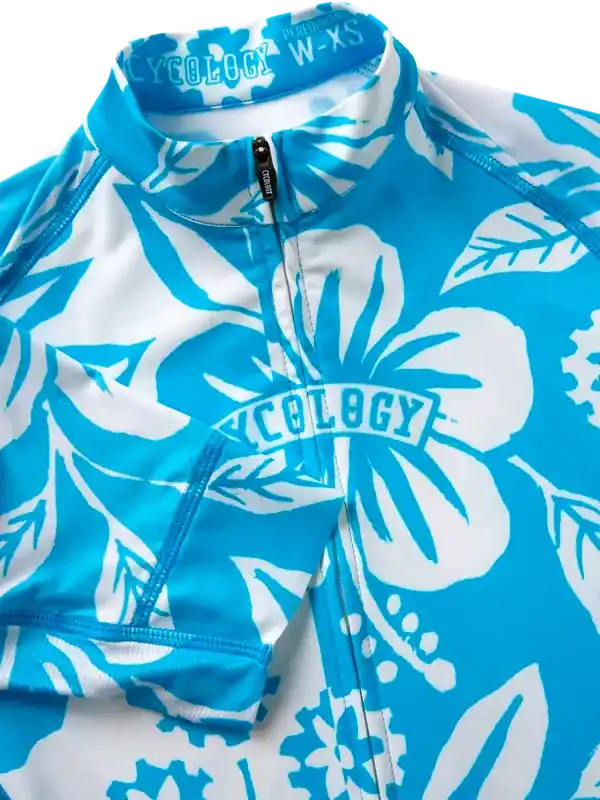 Blue and white floral women's cycling jersey with half-zip, featuring tropical hibiscus print and brand logo