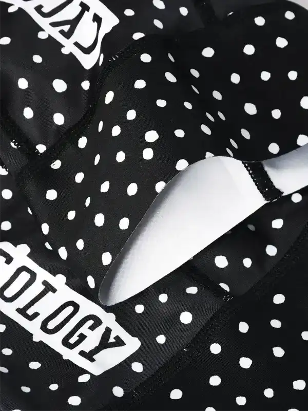 Black and white polka dot cycling shorts with bold graphic text, designed for comfort and style on rides.