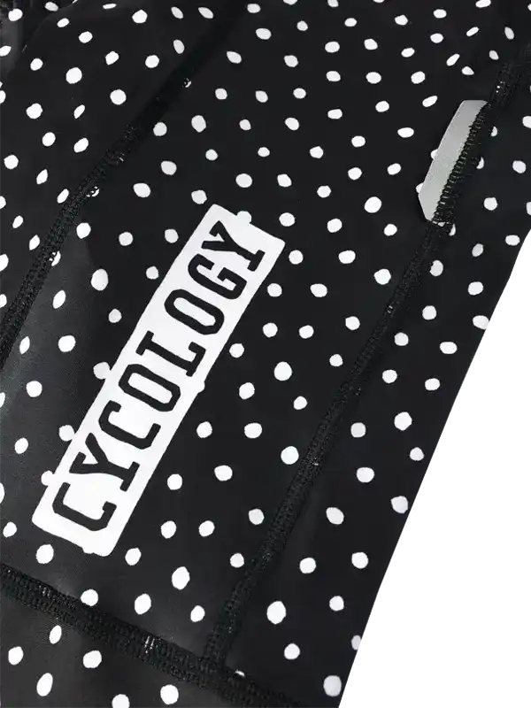 Black and white polka dot cycling jersey with 'CYCOLOGY' logo, featuring reflective zipper detail.
