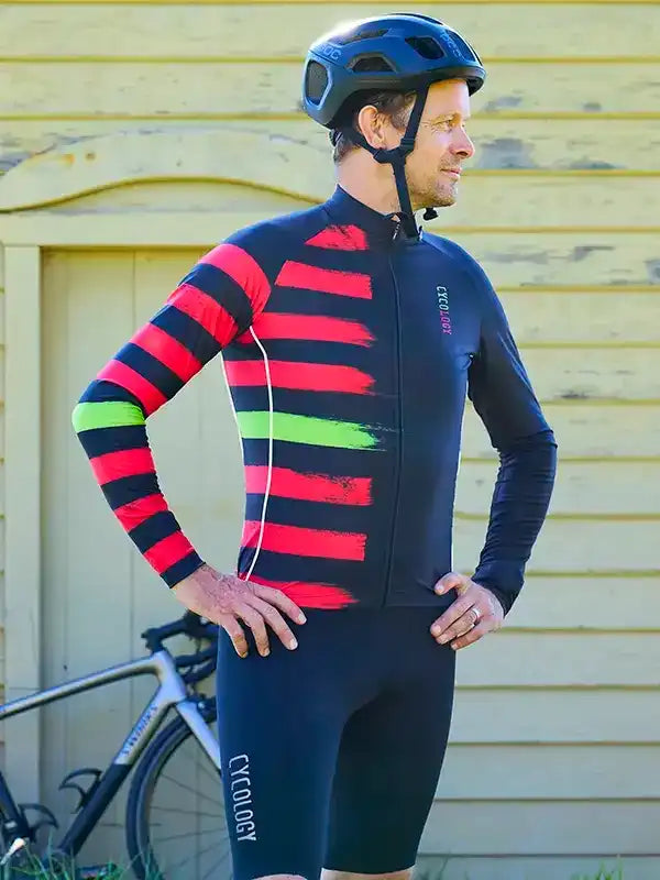 Men's cycling jersey with bold red, black, and green stripes, paired with matching bib shorts and helmet