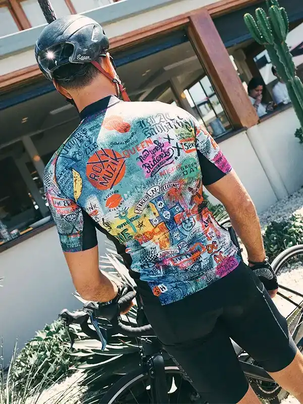 Men's colorful graphic cycling jersey with band logos, worn with helmet and bike outdoors