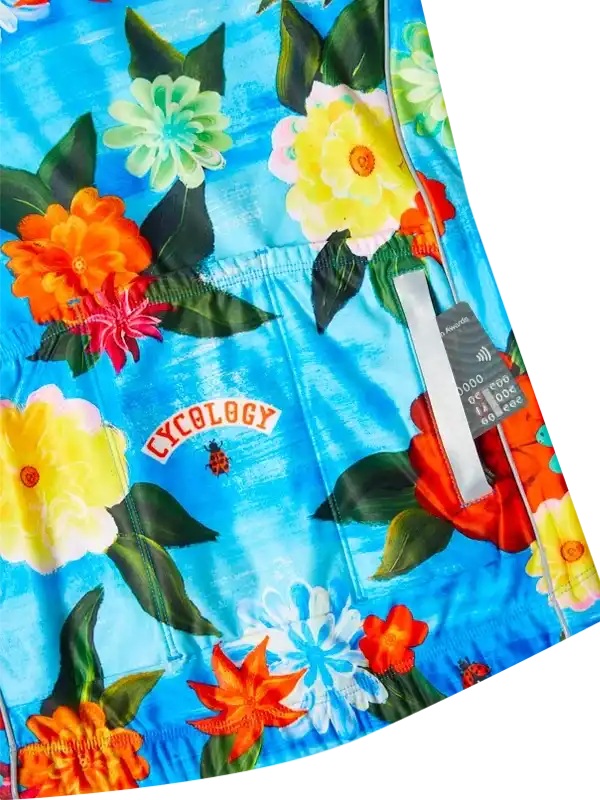 Vibrant floral cycling shorts with bold blooms on blue fabric, featuring Cycology logo and ladybug detail.