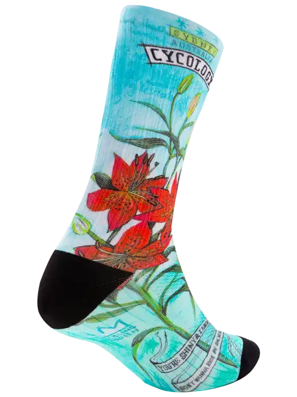 Cycling sock with red lily print, turquoise background, black toe and heel, floral design for bike rides
