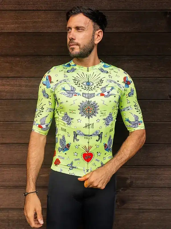 Men's lime green cycling jersey with tattoo-style bird and heart print, paired with black bib shorts