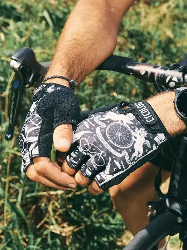 Cycling gloves with bike graphic print, worn on hands gripping bike handlebars outdoors