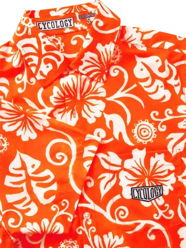 Vibrant orange cycling shirt with white floral and gear print, featuring Cycology logo on chest and collar.