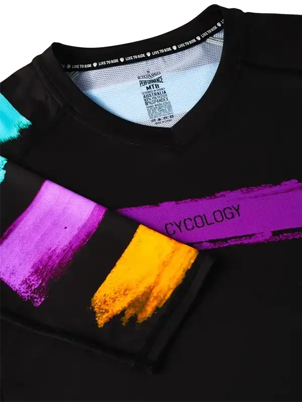 Black cycling jersey with vibrant purple, orange, and teal brushstroke design and 'CYCOLOGY' text