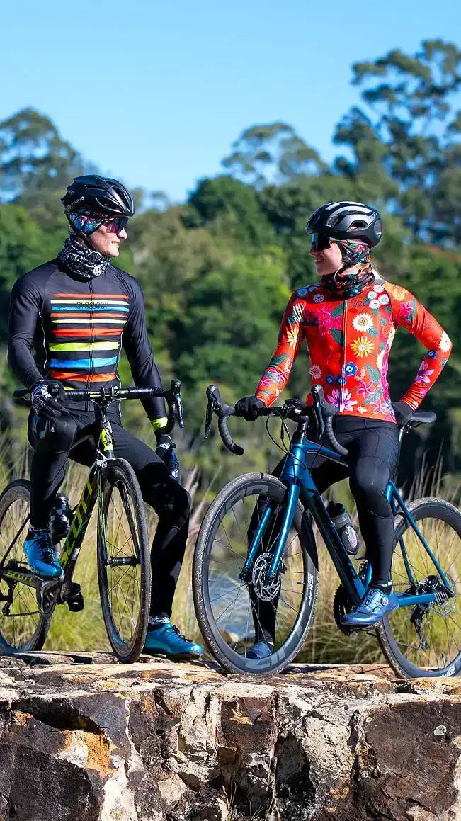 Man and woman in colorful cycling jerseys and helmets on bikes outdoors