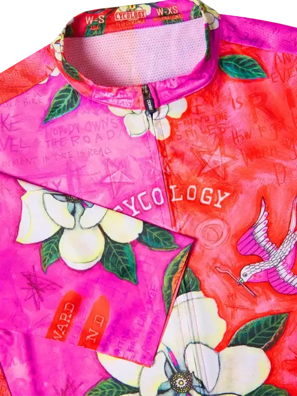 Vibrant pink and red women's cycling jersey with floral and bird print, featuring breathable mesh collar and zipper.