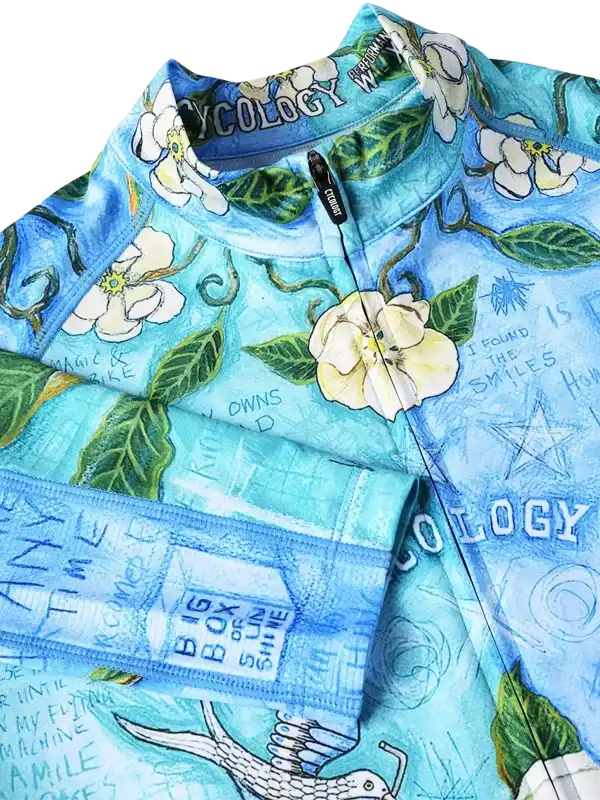 Blue floral cycling jersey with white flowers, green leaves, and inspirational text, featuring full-zip front and performance fabric.