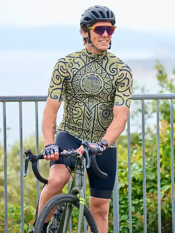 Man in patterned cycling jersey and shorts on road bike, wearing helmet and sunglasses outdoors