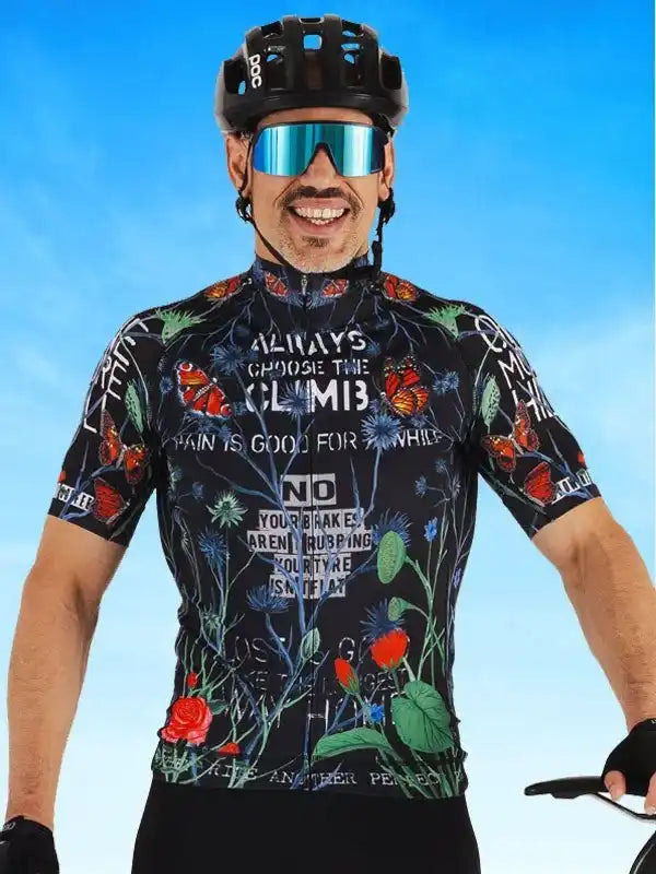 Man wearing floral cycling jersey with motivational text, helmet, and sunglasses against blue sky