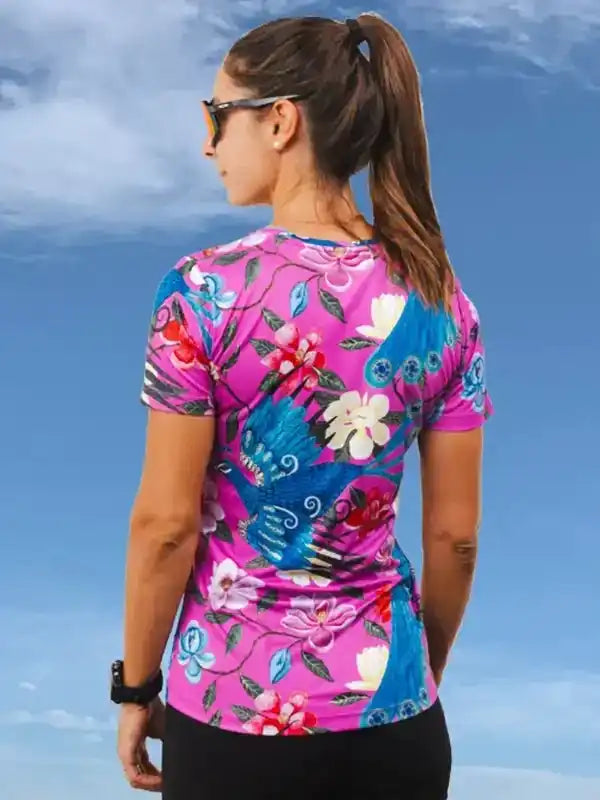 Woman wearing vibrant floral cycling jersey with blue bird design, ideal for bike rides
