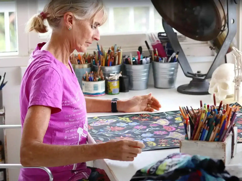 Woman designing floral cycling apparel in studio with colorful pencils and fabric swatches