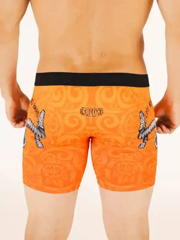 Men's orange cycling shorts with black waistband and graphic design, featuring unique patterns and brand logo