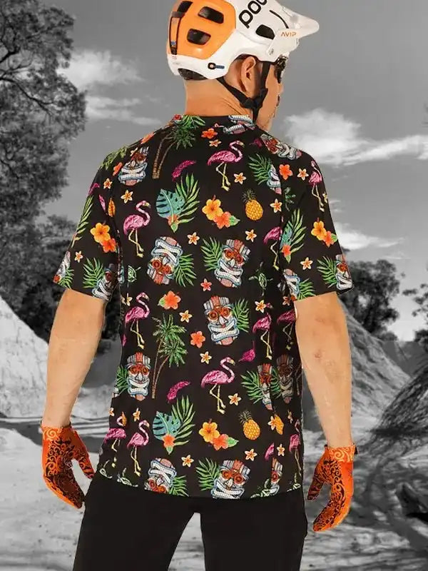 Men's tropical print cycling jersey with flamingos, pineapples, and tiki masks, worn with helmet and gloves