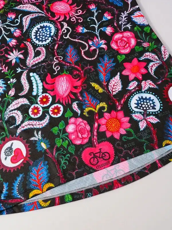 Vibrant floral cycling shorts with pink roses, bike motifs, and inspirational text on black fabric
