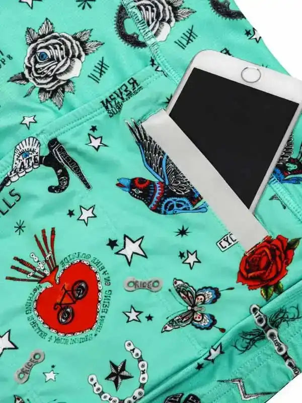 Mint green cycling shorts with tattoo-style graphics, roses, stars, and phone pocket for riders