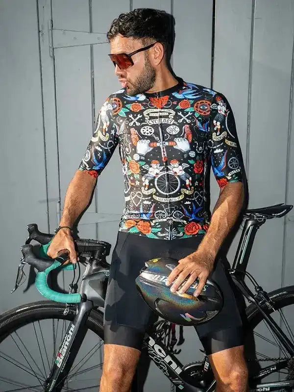 Man in colorful cycling jersey and shorts holding helmet beside road bike, stylish men's cycling apparel